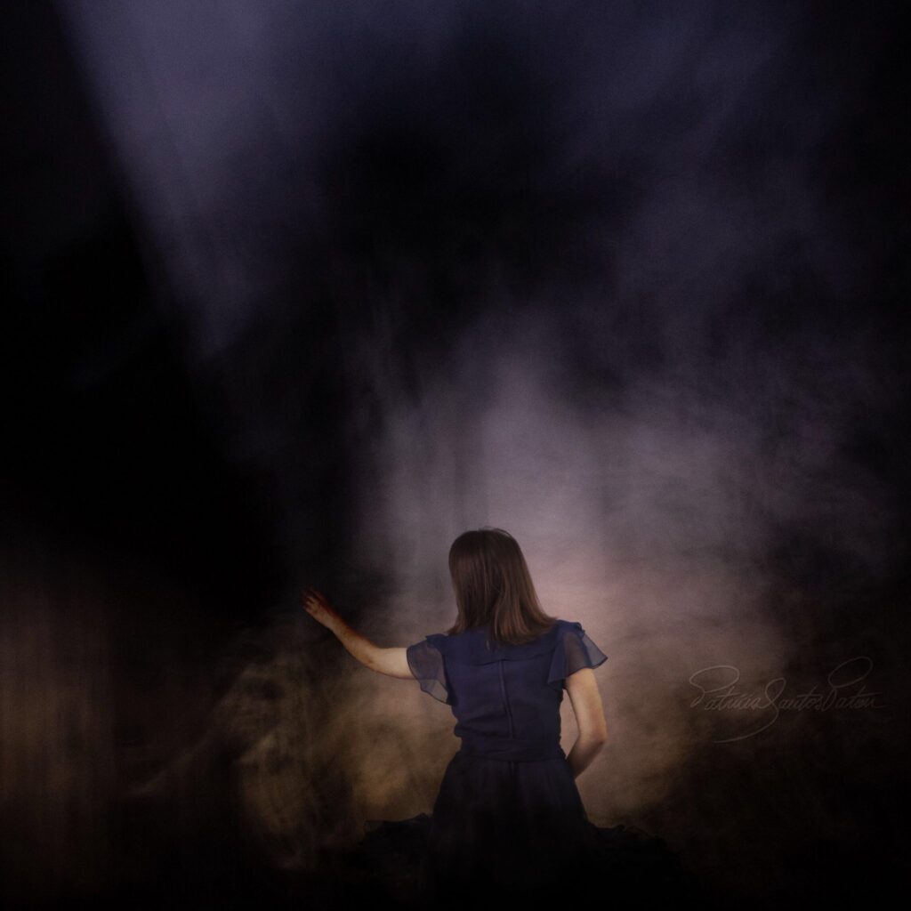 Intentional camera movement of a woman facing backwards with arm extended to darkness